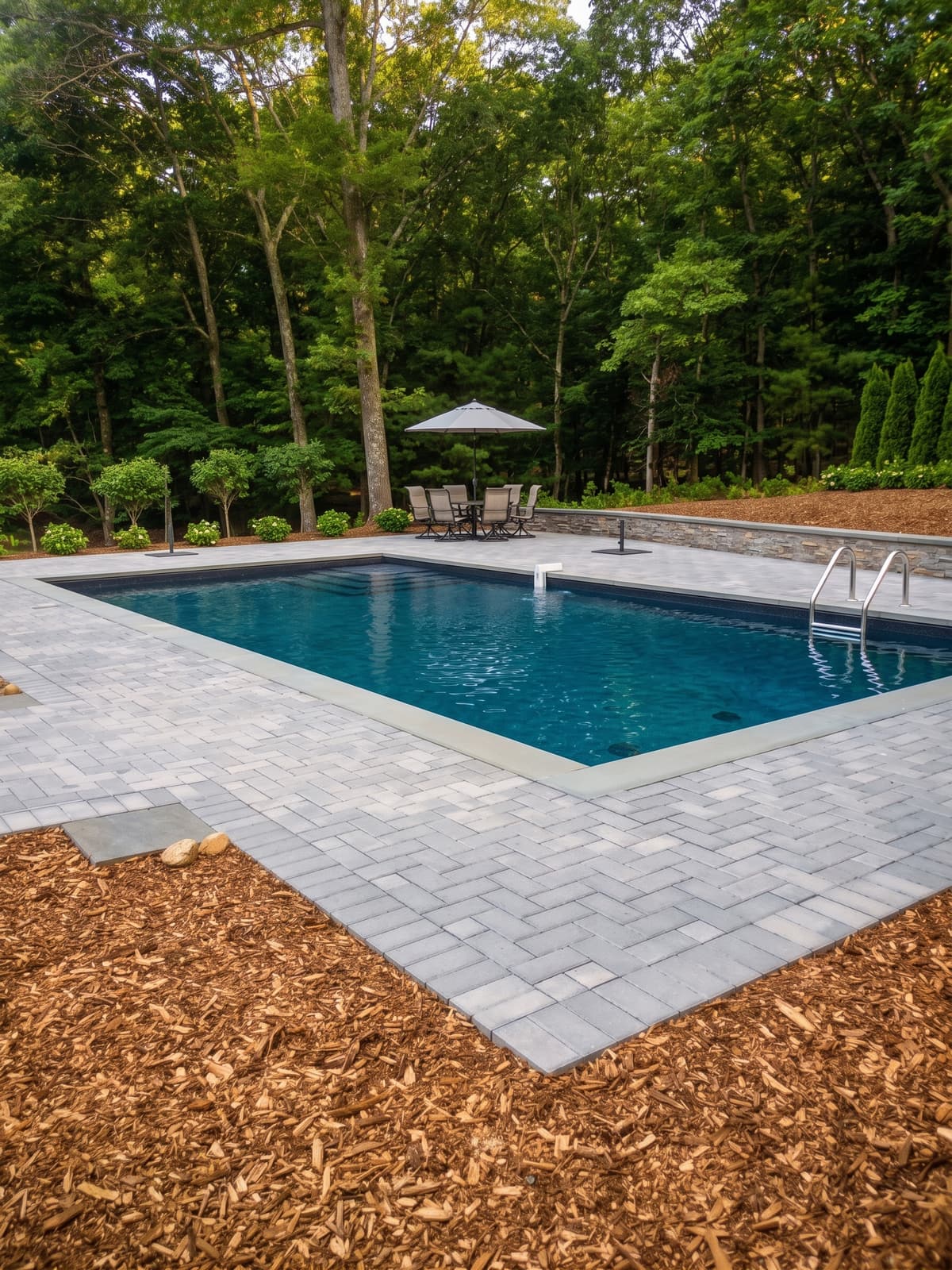 Inground pool with a paver patio surround and integrated landscaping