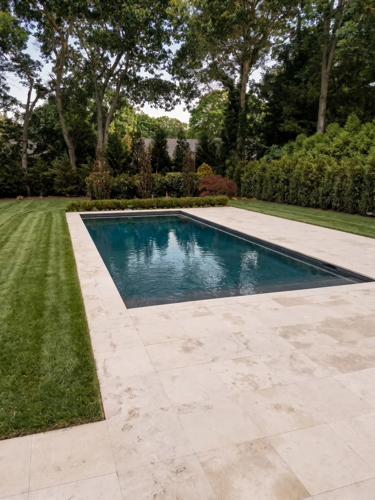 Modern rectangular gunite pool with travertine deck and clean coping
