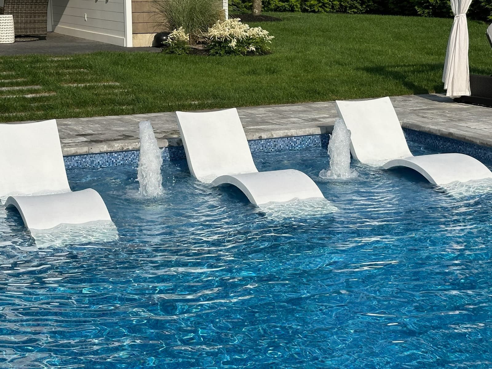 Tanning ledge with built-in loungers and a deck-jet water feature