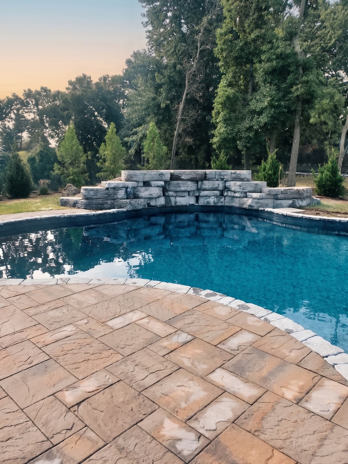 Natural stone waterfall feature cascading into an inground pool