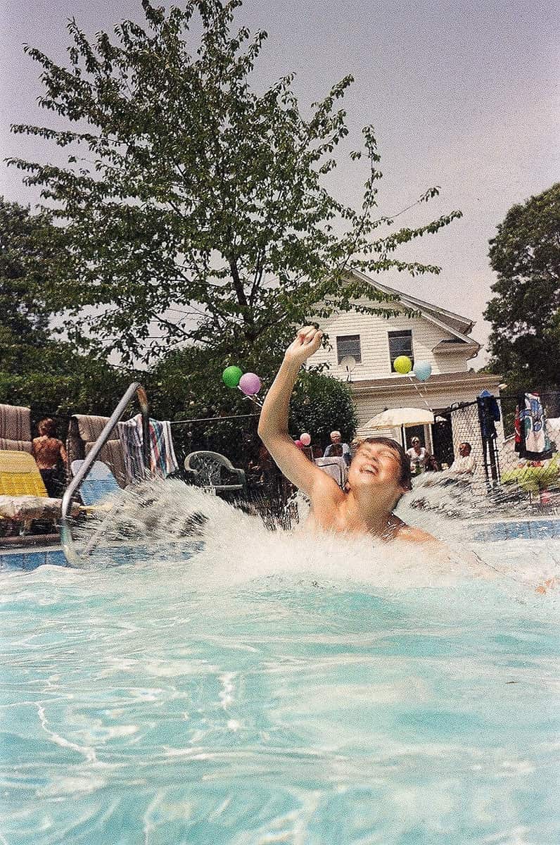 A family enjoying a cannonball splash in their pool