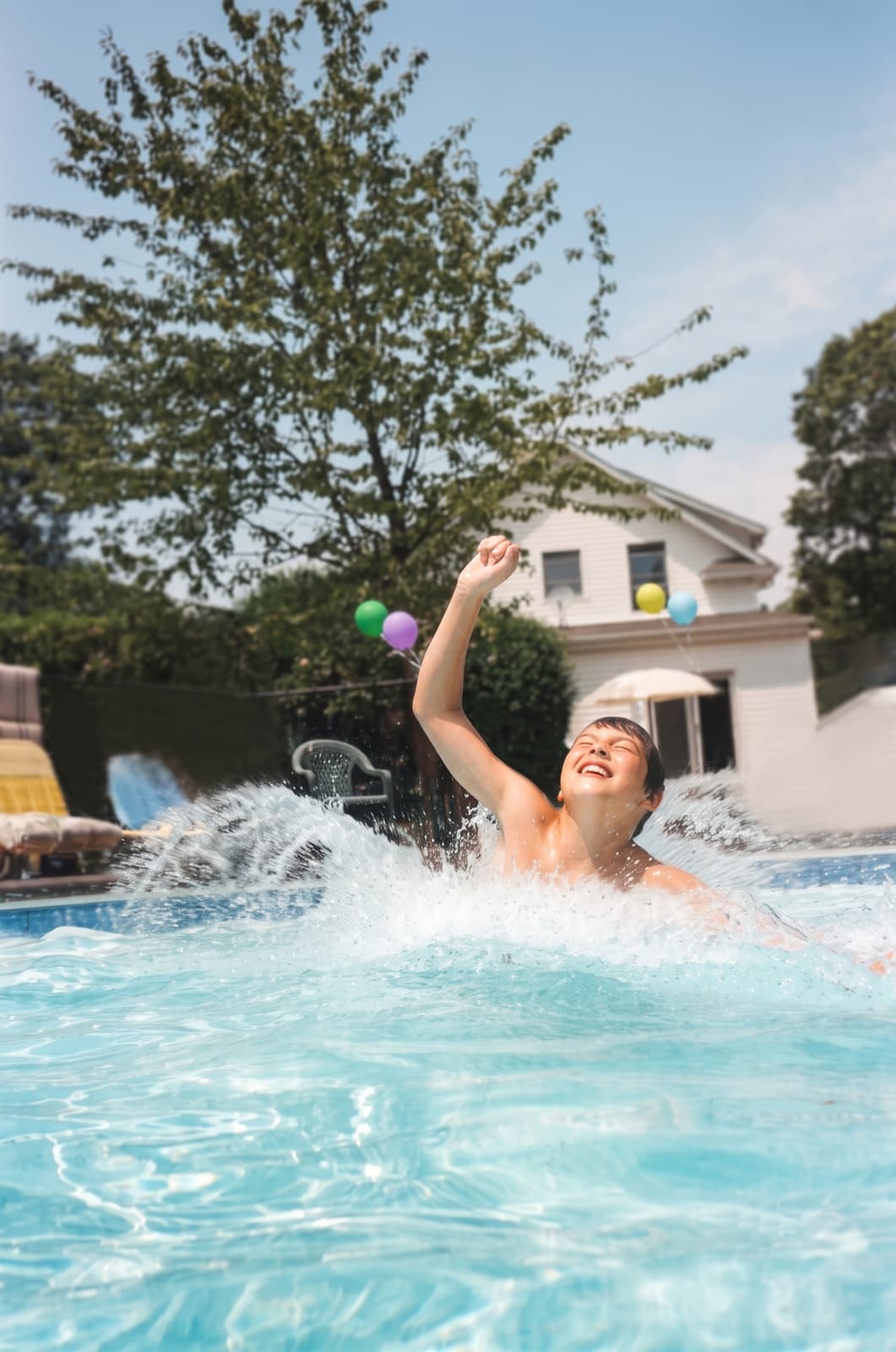 Kids leaping into a finished backyard pool on a summer day